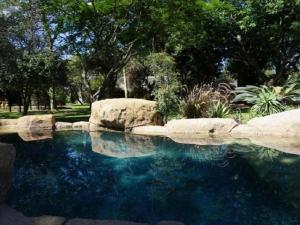 a pool of water with rocks in a yard at Kum Kula Lodge in Hoedspruit