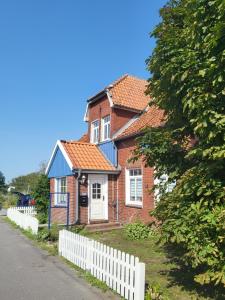 uma casa azul e vermelha com uma cerca branca em Urlaub im blauen Haus em Sehestedt