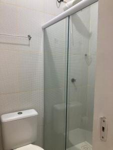 a bathroom with a toilet and a glass shower at Guaibim Residencial in Guaibim