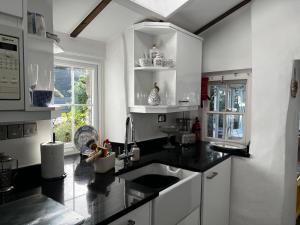 Beautiful Cottage in Llanfair with ocean views في Llanfair: مطبخ مع قمم منضدة سوداء ومغسلة