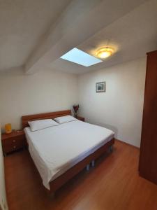 a bedroom with a large white bed with a skylight at Apartments Petani in Zadar