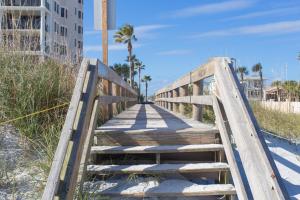 a wooden bridge over the sand at the beach at Cozy 2 Bedroom Home Minutes from Beach & Bars in Jacksonville Beach