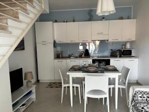 een keuken met witte kasten en een tafel en stoelen bij SPRITZ HOME in Viddalba