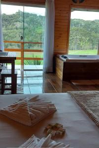 een slaapkamer met een bed, een bad en een tafel bij Pousada Recanto Das Araucárias in Bocaina do Sul