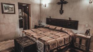 a bedroom with a bed and a cross on the wall at Hacienda Sepulveda Hotel & Spa in Lagos de Moreno