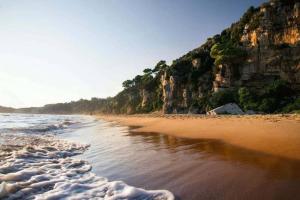 a beach with a cliff and the ocean at La rosa dei venti in Gaeta