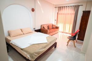 um quarto com uma cama e uma cadeira em Kana Kato em Aswan
