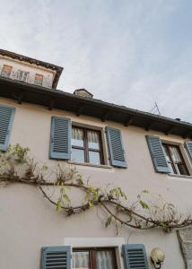 a building with blue shuttered windows and a tree at L&B HOUSE in Orta San Giulio