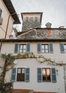 a white house with blue shutters on it at L&B HOUSE in Orta San Giulio