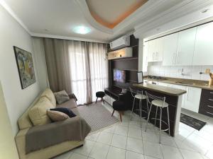 a living room with a couch and a kitchen at Apartamento central c/ Garagem e Wi-fi in Criciúma