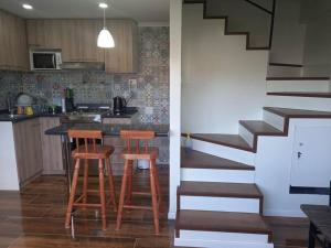 a kitchen with two stools and a kitchen with a staircase at Cabañas y Departamentos Las Palmas, Temuco Depto 1 in Temuco