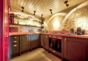a kitchen with purple cabinets and a stone wall at The Rock House - Terrace Apartment - in Heart of the City in Edinburgh