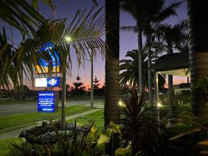 a sign in front of a building with palm trees at Coastal Waters Motor Inn in Lakes Entrance