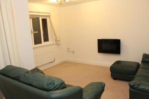 a living room with a couch and a television at Elegant Guest House in Spinney Hill