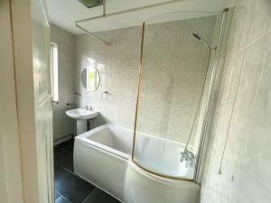 a white bathroom with a tub and a sink at pinner apartments in Pinner