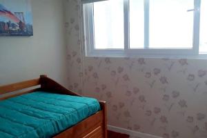 ein Schlafzimmer mit einem Bett mit einer blauen Decke darauf in der Unterkunft Depto. frente a la playa con hermosa vista al mar y faro La Serena in La Serena