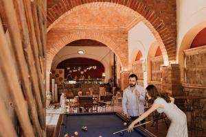 a man and a woman playing pool in a restaurant at Hacienda Sepulveda Hotel & Spa in Lagos de Moreno