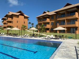 a resort with a swimming pool with chairs and umbrellas at ECO RESORT PRAIA DOS CARNEIROS - NOVÍSSIMO in Tamandaré
