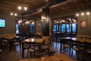 a restaurant with wooden tables and chairs and windows at Vila Muslli in Korçë