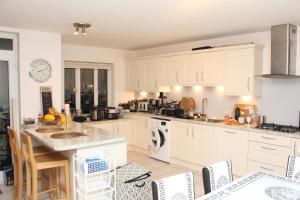 una cocina con armarios blancos y una mesa con sillas. en Elegant Guest House en Spinney Hill