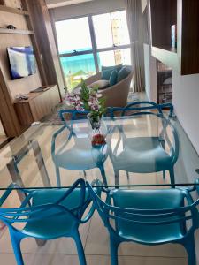 2 sillas azules y una mesa de cristal en la sala de estar. en Apartamento Duplex Vista Mar em Natal, en Natal