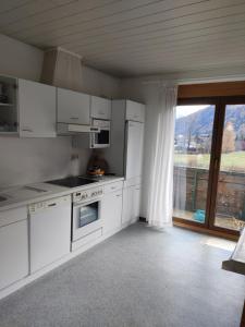 eine Küche mit weißen Geräten und einem großen Fenster in der Unterkunft Landhaus Penker in Mallnitz