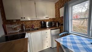 eine Küche mit weißen Schränken, einem Tisch und einem Fenster in der Unterkunft Sjöstuga vid Bunn Gränna - Uddastugan in Gränna
