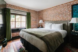 a bedroom with a large bed and a brick wall at Granada Hotel & Bistro in San Luis Obispo
