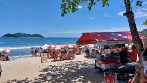 a beach with umbrellas and people on the beach at Maury Chalés Boiçucanga in São Sebastião