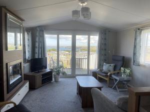 a living room with a television and a balcony at CP1 Caravan, Howelston Holiday Park in Haverfordwest