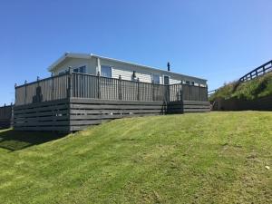 a house sitting on top of a grassy hill at CP1 Caravan, Howelston Holiday Park in Haverfordwest