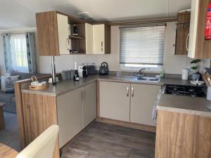 a kitchen with wooden cabinets and a counter top at CP1 Caravan, Howelston Holiday Park in Haverfordwest