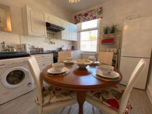 a kitchen with a wooden table and a white refrigerator at Regent Apartment 1 in Blackpool