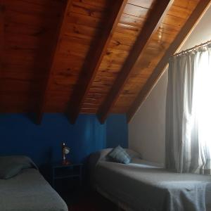 1 dormitorio con 2 camas y techo de madera en Cabañas Huenco en El Calafate