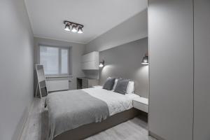 a white bedroom with a bed and a window at Alunana Suites in Rīga