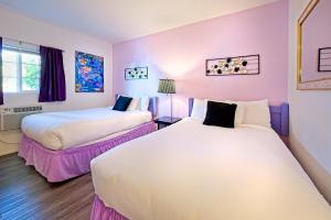 two beds in a room with purple walls at Inn at Palm Springs in Palm Springs