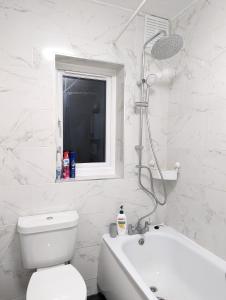 een witte badkamer met een toilet en een bad bij The Saxon Rooms in Barking