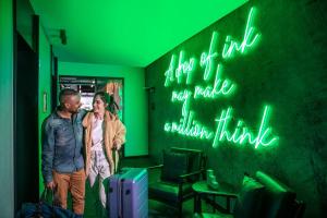 un uomo e una donna in piedi in una stanza con i bagagli di Ink Hotel Melbourne Southbank a Melbourne