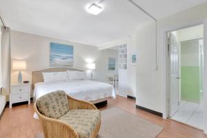 Seahorse Guesthouse في بومبانو بيتش: غرفة نوم بيضاء بسرير وكرسي