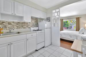 a kitchen with a sink and a refrigerator and a bed at Seahorse Guesthouse in Pompano Beach