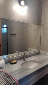 La salle de bains est pourvue d'un lavabo et d'un grand miroir. dans l'établissement Céu da Canastra, à Delfinópolis