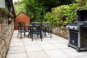 a patio with a table and chairs and a grill at The Coach House at Lower Coombe Royal- Family/Dogs in Kingsbridge