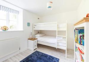 a bedroom with a white bunk bed and a blue rug at The Coach House at Lower Coombe Royal- Family/Dogs in Kingsbridge