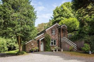 a brick house with a tree and a driveway at The Coach House at Lower Coombe Royal- Family/Dogs in Kingsbridge