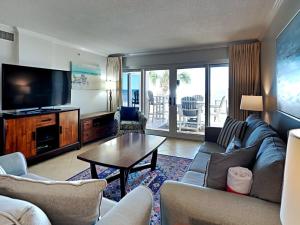 a living room with a couch and a tv and a table at Sandy Key #223 in Perdido Key