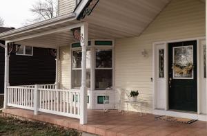 une terrasse couverte à l'avant d'une maison avec une porte verte dans l'établissement Bell House on Madison Lake, à Elysian
