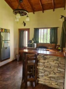 cocina con barra con pared de piedra en Cabaña en los Acantilados, en Mar del Plata