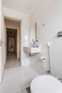 a white bathroom with a toilet and a sink at Apartamento encantador no Guarujá, praia da Enseada - Apenas 600m da praia ! in Guarujá