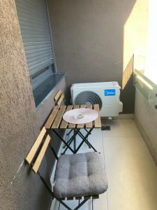 a balcony with a table and chairs and a heater at Apartment IRIS in Novi Sad