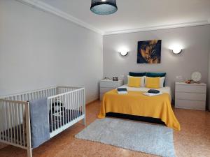 une chambre avec un berceau avec une couverture jaune dans l'établissement Villa Margot: grande moradia com piscina, à Olhão